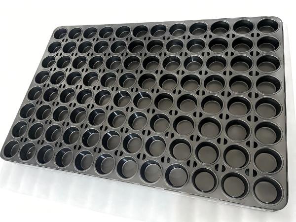 A person in a kitchen supply store comparing several different types of baking pans